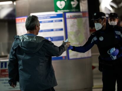 Agentes de la Policía Municipal de Madrid reparten mascarillas a los viajeros en la estación de metro de Sol.