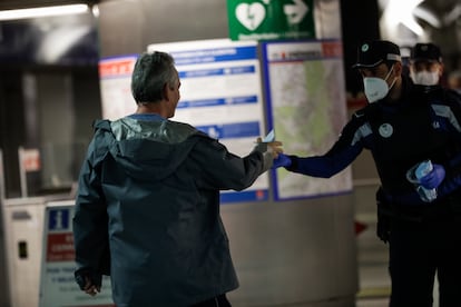 Agentes de la Policía Municipal de Madrid reparten mascarillas a los viajeros en la estación de metro de Sol, este lunes.