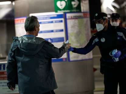 Agentes de la Policía Municipal de Madrid reparten mascarillas a los viajeros en la estación de metro de Sol, este lunes.