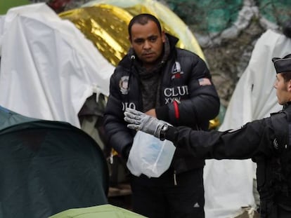 Un agente francés hace un gesto a un migrante durante el desalojo de un campo en el centro de París, el pasado 4 de junio.