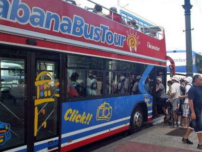 Turistas abordan un autob&uacute;s tur&iacute;stico en una calle de La Habana (Cuba).