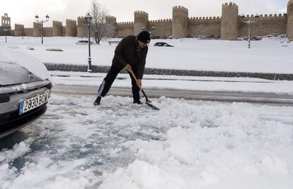 Un hombre retira nieve con una pala frente a la murallas de Ávila. 