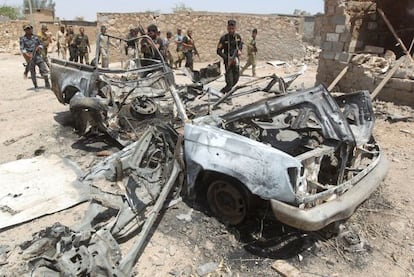 Fuerzas gubernamentales inspeccionan los restos calcinados de un coche en la ciudad de Tikrit el pasado lunes.