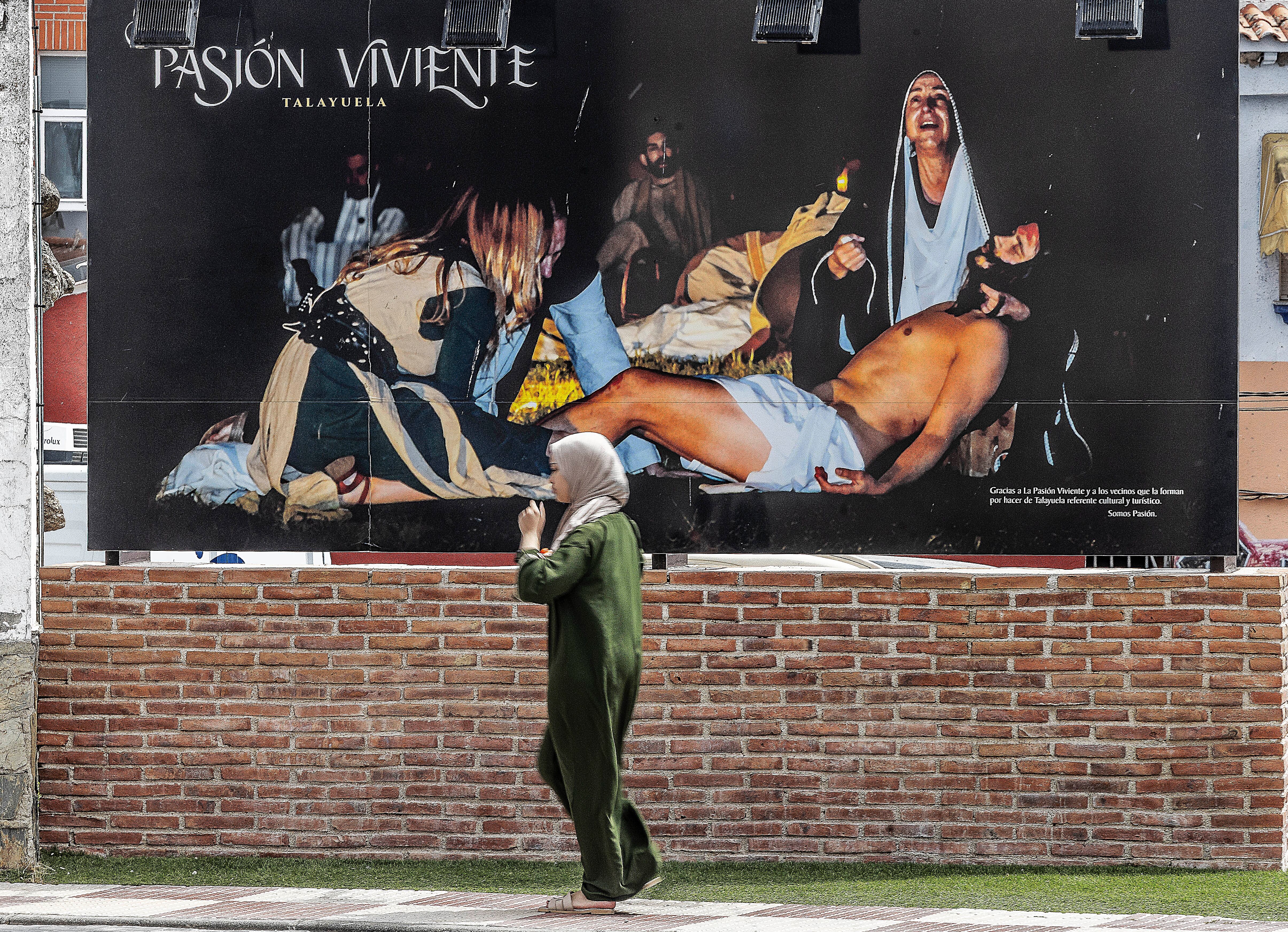Una mujer pasa junto a una cartel anunciando la Pasión Viviente de Semana Santa en la localidad extremeña de Talayuela, este viernes. 