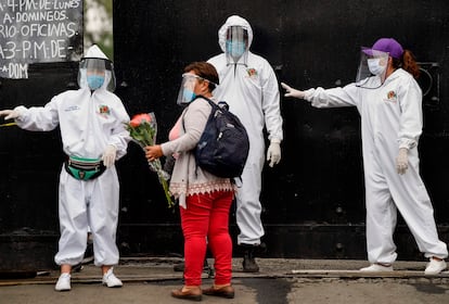 Empleados del Gobierno de la Ciudad de México dan indicaciones a la entrada de un cementerio.