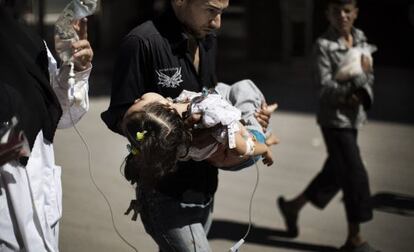 Un hombre lleva en sus brazos una niña herida en Alepo.