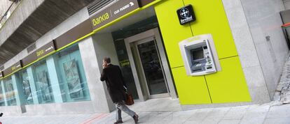 Un hombre caminando delante de una oficina de Bankia