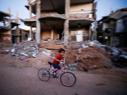 Un niño pasa en bicicleta ante una casa destruida por los bombardeos, el domingo en Gaza.