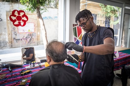 Sadou, un joven camerunés solicitante de asilo, corta el pelo a una persona que ha acudido al Centro Dignidad de la ONG Refugee Support para utilizar este servicio gratuitamente. 