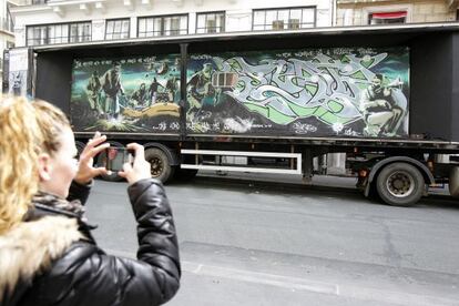 Una mujer fotografía el remolque con el grafiti de Banksy.