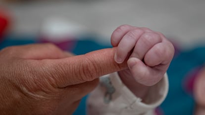 Un bebé sostiene la mano de una cuidadora en la guardería en Washington D.C.