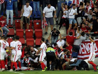 Aficionados del Sevilla caen al césped tras ceder una valla en Ipurúa este sábado.