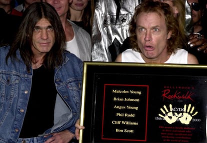 Os integrantes da banda AC/DC Angus Young (direita) e seu irmão Malcolm mostram uma placa após deixar as mãos impressas no Passeio da Fama do Rock em Hollywood, em 2000.