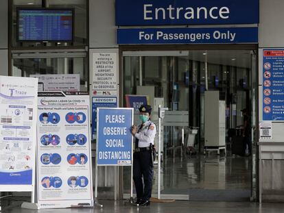 Una agente de seguridad del aeropuerto de Manila, el miércoles junto a las instrucciones de control de la pandemia.