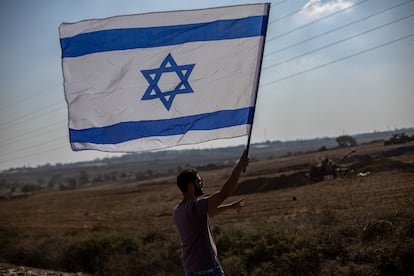 Un hombre ondea la bandera de Israel en la frontera con Gaza