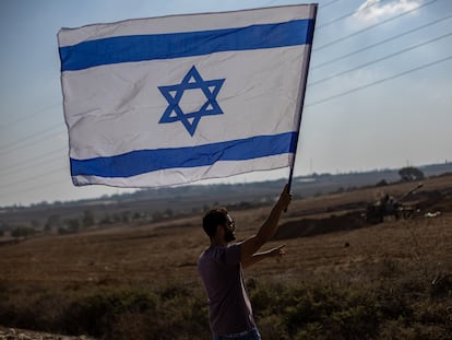 Un hombre ondea la bandera de Israel en la frontera con Gaza