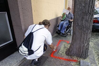 An activist paints a red line on a suspect sidewalk.