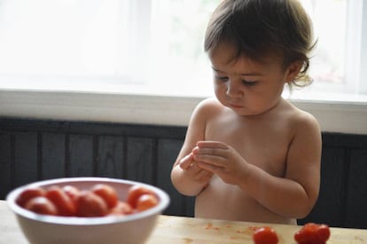 Niña cocinando con tomates.