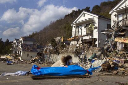 Una mujer llora junto al cadáver de su madre, recién recuperado entre las ruinas de su casa, en Onagawa.