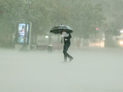 Un hombre camina bajo una intensa lluvia este viernes en Valencia.