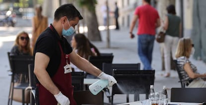 Un camarero desinfecta una mesa tras las marcha de los clientes la terraza de un bar del centro de Madrid.