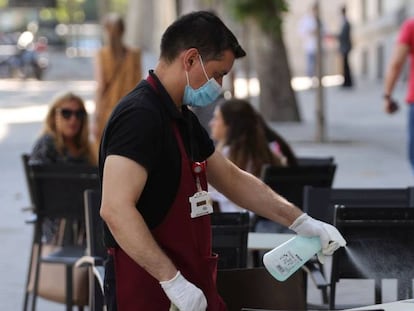 Un camarero desinfecta una mesa tras las marcha de los clientes la terraza de un bar del centro de Madrid.