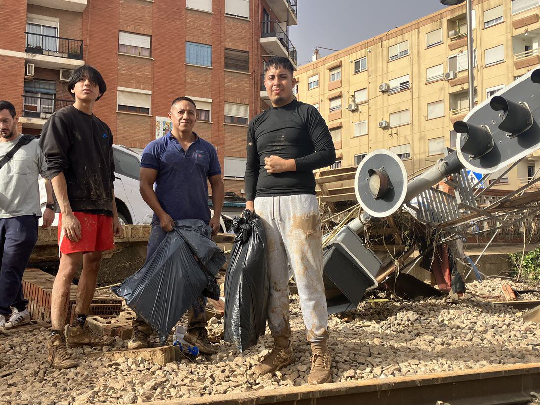 Jeovany Moreto y sus hijos, frente a los escombros que ha dejado la riada en Alfafar, Valencia, este miércoles.