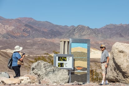 Rebecca Rivera le toma una foto de su esposo Joaquim Rivera  junto a una pantalla digital que da una lectura de calor no oficial en Furnace Creek. 