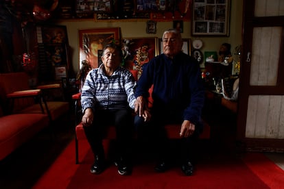 Blanca Soria y Gerardo Alarcón en la sala de su casa sentados frente a cuadros de la Virgen Inmaculada, matrona de los artesanos de Guano, Ecuador.