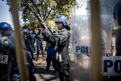 Los policías antimotines zimbabuenses montan guardia y cierran la puerta de las Rainbow Towers. donde se anunciaron los resultados de las elecciones, tras el estallido de una protesta del partido opositor.