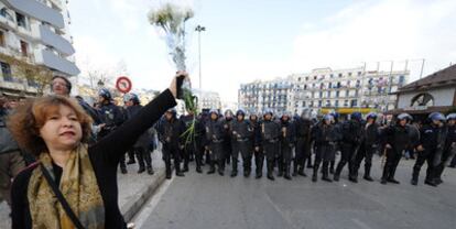 Una manifestante levanta unas flores ante un cordón de policías antidisturbios desplegados en el centro de la capital argelina.