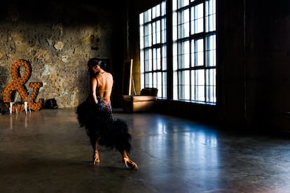 Girl dancing ballroom dance in big dark hall.