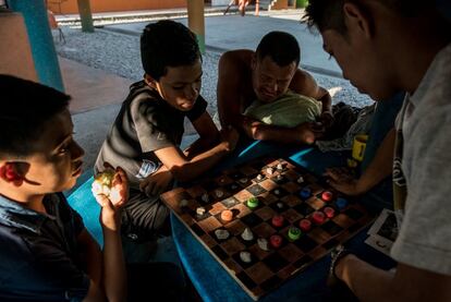 Migrantes pasan el tiempo y se relajan con juegos de mesa mientras esperan a un tren de carga en el refugio de Tenosique. 