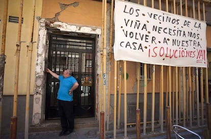 Un hombre llama al telefonillo en un bloque de apartamentos donde se ven las marcas del terremoto.