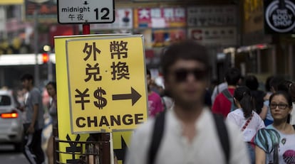 Viandantes junto al cartel de una oficina de intercambio divisas en Hong Kong (China).