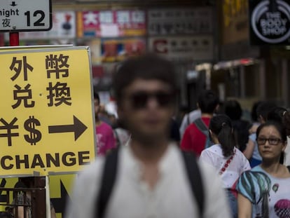 Viandantes junto al cartel de una oficina de intercambio divisas en Hong Kong (China).