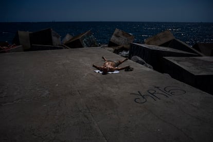 Un hombre toma el sol en un rompeolas en Barcelona, España, miércoles 9 de agosto de 2023.