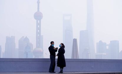 Una pareja con mascarilla frente al distrito financiero de Pudong, en Shanghái, este lunes.