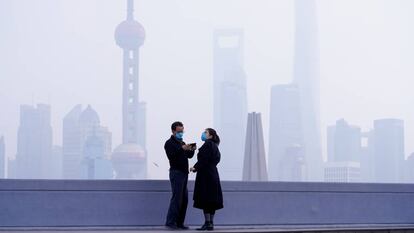Una pareja con mascarilla frente al distrito financiero de Pudong, en Shanghái, este lunes.