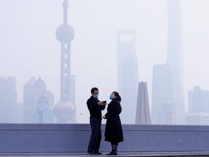 Una pareja con mascarilla frente al distrito financiero de Pudong, en Shanghái, este lunes.