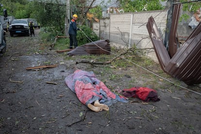 Un cadáver cubierto con una manta yace en la calle de un barrio residencial tras el bombardeo ruso, este domingo, 
 en Járkov (Ucrania).