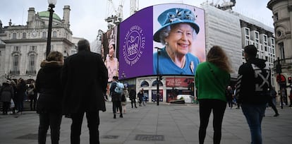 Varios viandantes observan las imágenes de la reina Isabel II, en Picadilly Circus, este domingo.