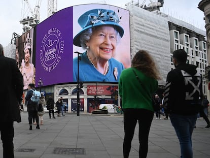 Varios viandantes observan las imágenes de la reina Isabel II, en Picadilly Circus, este domingo.