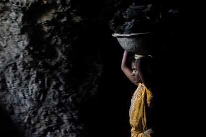 Una mujer carga con carbón en un espacio reducido y poco iluminado de una gruta. Sabedores de formar parte de una industria ilegal, las familias no informan de las muertes por derrumbamiento.