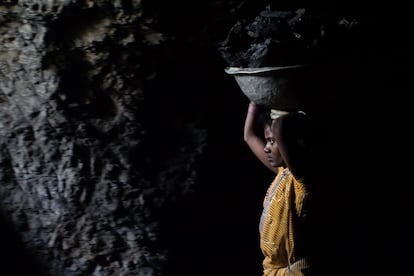 Una mujer carga con carbón en un espacio reducido y poco iluminado de una gruta. Sabedores de formar parte de una industria ilegal, las familias no informan de las muertes por derrumbamiento.