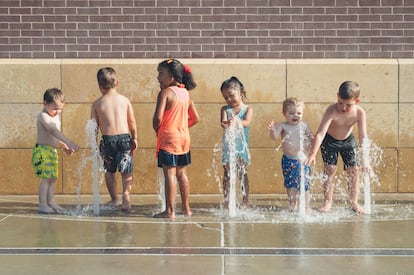 Un grupo de niños juega en una fuente.