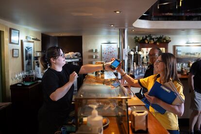 La cartera Elena Olivar, durante la entrega del voto por correo a Teresa Berrocal en el bar donde trabaja en Medina del Campo.