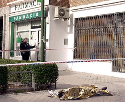 Un policía observa el cadáver del toxicómano fallecido en el tiroteo