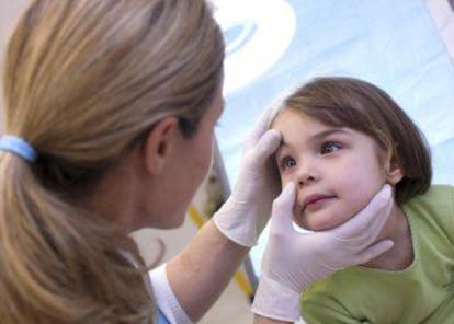 Una oftalmóloga revisa los ojos de un niño.