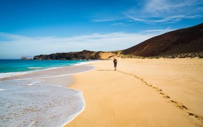 Senderista en la playa de Las Conchas, en la isla de La Graciosa, en Lanzarote.